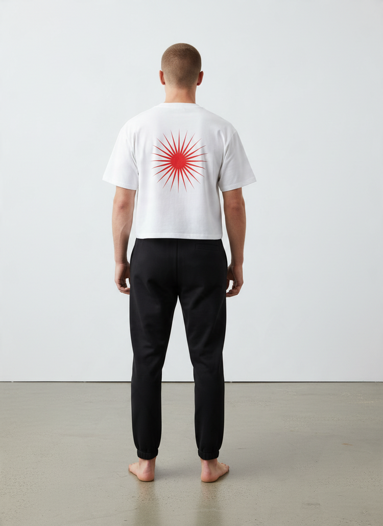 SANDERS Cycling white boxy tee with red sunburst graphic on the back, worn with black joggers